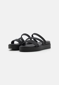 Sandales noires à plateforme avec des sangles tressées texturées et une semelle plate. Présente des sangles croisées larges et un semelle intérieure lisse.