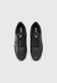 Black leather sneakers with a smooth surface, round toe, and flat laces. Features subtle stitching and a white rubber sole.