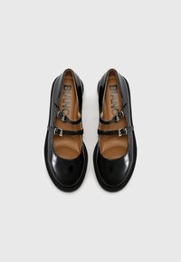 Schwarze Lacklederschuhe mit braunen Innensohlen, ausgestattet mit zwei Schnallenriemen und runden Zehen, glatte Oberfläche und strukturierte Sohlen.