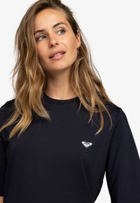 Black short-sleeve t-shirt made of soft fabric, featuring a white logo on the left chest. Simple design with a crew neckline.