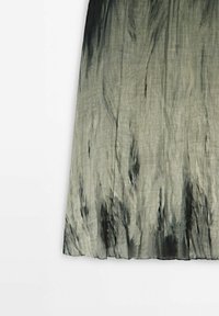 Jupe maxi en tissu léger, présentant un dégradé de gris et noir avec une texture douce et un motif tie-dye subtil.