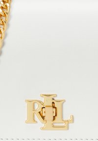 Borsa in pelle bianca con una chiusura dorata che presenta le lettere "RL". Texture liscia con una finitura lucida e dettagli con tracolla a catena.