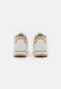 Beige og hvite joggesko med en glatt overdel i lær og tekstil, med lavprofil-design og minimale detaljer.