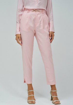 Pantalons sur mesure rose pâle avec des plis, une ceinture assortie avec une boucle en or et des fentes sur les ourlets. Texture de tissu lisse.