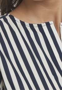 Tela a rayas azul marino y blanca en primer plano, con una textura suave, cuello redondo y detalle de costura sencilla.