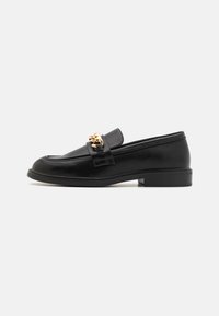 Black leather loafer with a low block heel, featuring a gold chain accent on the front and smooth texture. Rounded toe design.