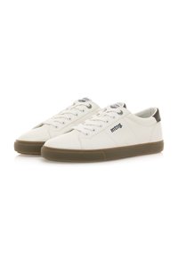 Zapatillas de cuero blanco con suela de goma marrón, punta redonda y cierre de cordones; presentan un logo en el lateral y un acento en el talón en contraste.