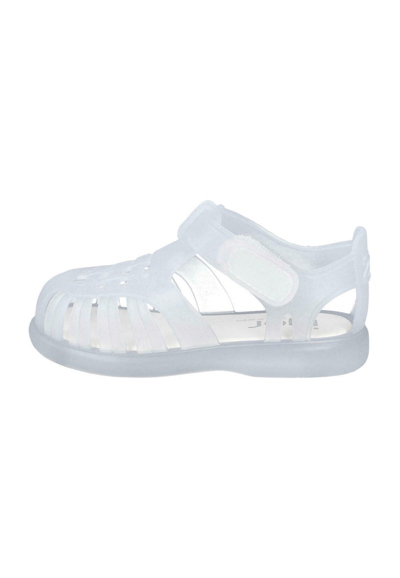 Sandalias blancas translúcidas con punta cerrada y lados abiertos, que cuentan con una correa de Velcro y un diseño ranurado para ventilación.
