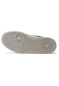 Semelle en caoutchouc blanche avec motif de grip texturé et détail circulaire. Logo notable embossé dans la zone du talon. Design plat avec des bords lisses.