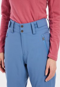 Blue ski pants with a fitted design, featuring a smooth texture, two button closure, adjustable waistband, and zippered side pockets.