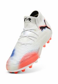 Weiße Fußballschuhe mit einer strukturierten Oberseite, featuring blaue und rote Farbverläufe und orangefarbigen Stollen. Schwarzes Logo an der Seite.