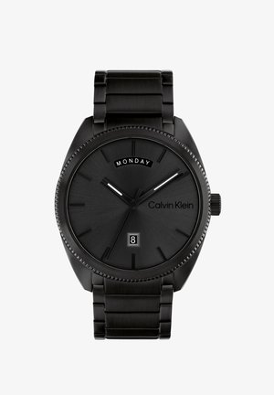 Ρολόι Calvin Klein από μαύρο ατσάλι με στρογγυλή κάσα, μίνιμαλ δείκτες ωρών, ημερήσια ένδειξη στις 12 η ώρα και παράθυρο ημερομηνίας στις 6 η ώρα.