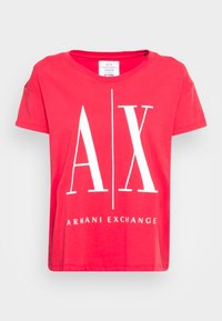 Czerwona koszulka z krótkim rękawem z bawełny, z dużym białym logo "AX" i napisem "ARMANI EXCHANGE" na dole. Okrągły dekolt i luźny krój.