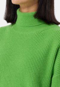 Grüner gestrickter Rollkragenpullover mit einem strukturierten, gerippten Muster. Hat einen hohen Kragen und lange Ärmel und präsentiert lebendige Farben sowie ein weiches Material.