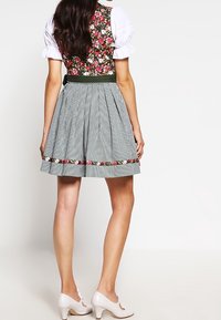 Traditionele dirndl jurk met een bloemenpatroon op het lijfje en een grijs ruitjesrok. Heeft een tailleband met bloemenaccents en witte pofmouwen.