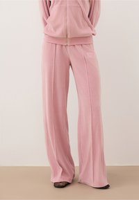 Roze velours trainingsbroek met een wijde pijpdesign, met subtiele borduursels en een gladde, zachte textuur.