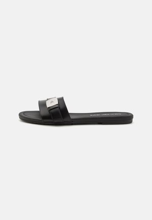 Black flat slide sandal with two wide straps, featuring a metallic accent. Smooth synthetic material and flat rubber sole.