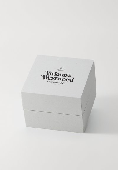Τετράγωνο, γκρίζο κουτί με υφή που διαθέτει μαύρο εκτυπωμένο κείμενο: "Vivienne Westwood TIME MACHINE," μινιμαλιστικός σχεδιασμός.