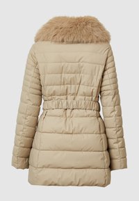 Beige Pufferjacke mit einem Kragen aus Kunstfell, gestepptem Design, taillierter Passform und langen Ärmeln, konzipiert für Wärme und Komfort.
