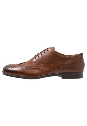 Chaussure de ville en cuir marron pour homme avec détails brogue, lacets et petit talon, vue de profil sur fond blanc.