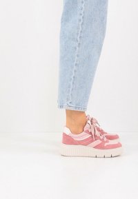 Ροζ σουέντ και δίχτυ αθλητικά παπούτσια με παχιά λευκή σόλα, με σχέδιο με κορδόνια και ριγέ λεπτομέρειες. Συνδυασμένα με ανοιχτού μπλε τζιν με γυρισμένα μπατζάκια.