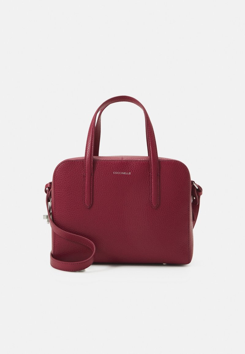 Sac à main rouge en cuir texturé de taille moyenne avec deux poignées et une bandoulière amovible, marqué "Coccinelle" sur le devant.