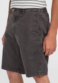 Grijze katoenen shorts met een ontspannen fit, voorzien van een knoopsluiting, zijzakken en gestikte accenten. De stof heeft een zachte, gestructureerde afwerking.