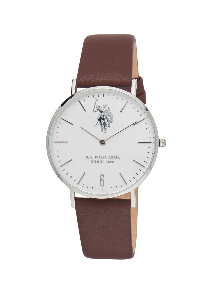 Orologio rotondo con quadrante bianco, hardware argentato, cinturino in pelle marrone e grafica di un giocatore di polo. Il display include indici delle ore e il numero sei.