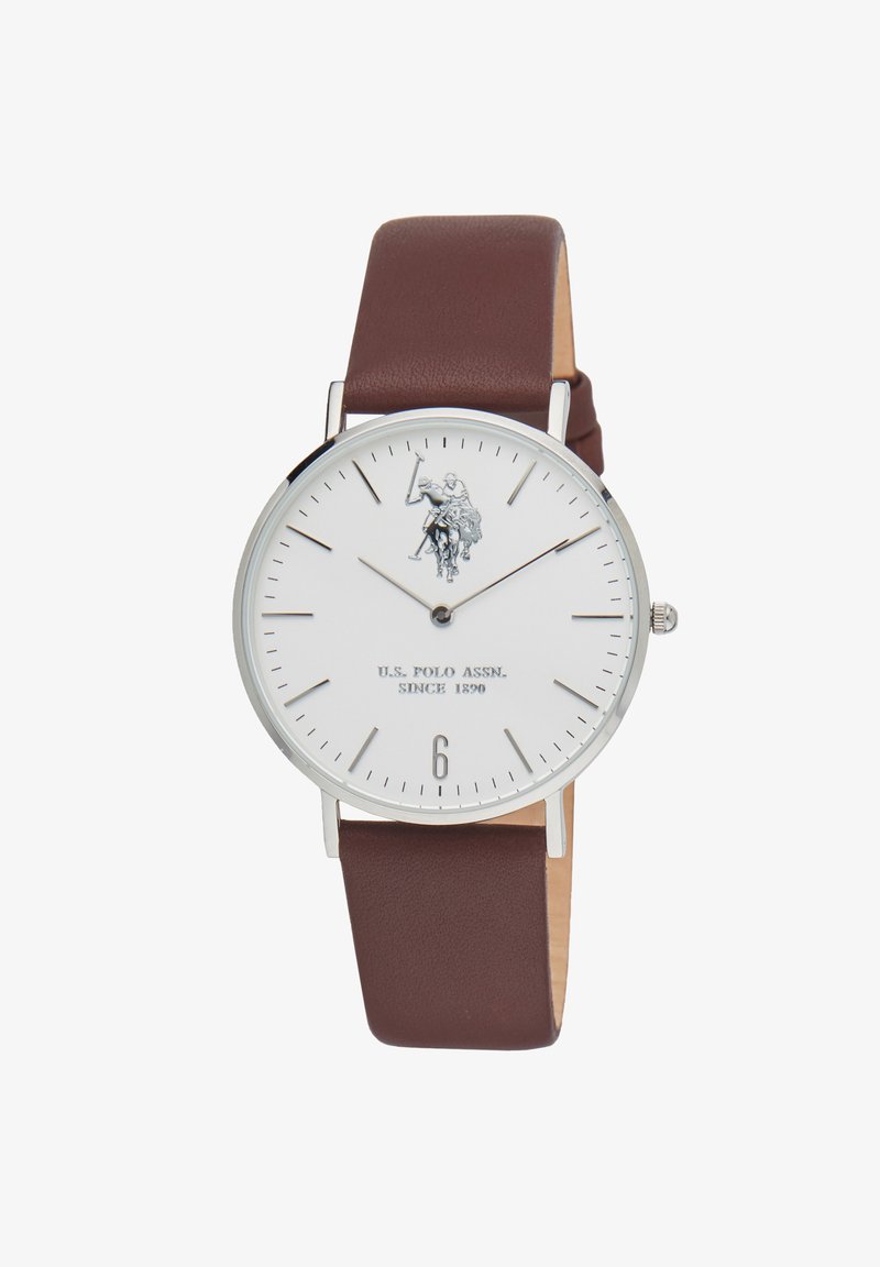 Orologio rotondo con quadrante bianco, hardware argentato, cinturino in pelle marrone e grafica di un giocatore di polo. Il display include indici delle ore e il numero sei.