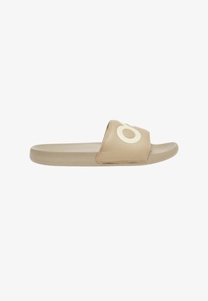 Beige open-toe slidesandaal met een brede band met een grote witte gestileerde letter "O" en een gevormd voetbed.