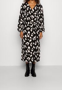 Svart och vit omlottklänning med leopardmönster, med långa ärmar och midilängd. Matchad med svarta klackstövlar.