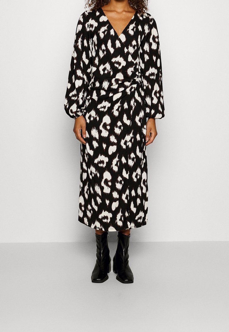 Svart och vit omlottklänning med leopardmönster, med långa ärmar och midilängd. Matchad med svarta klackstövlar.