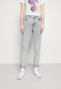 Ljusgrå avslappnade jeans i denim med uppvikta fickor. Har två framfickor och knäppning med knapp. Kombineras med vita sneakers.