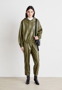 Ensemble de survêtement en vinyle vert olive avec capuche, doté d'une taille élastique, d'une coupe décontractée et de bottines noires. Design simple et moderne.