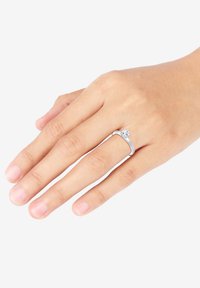 Ehering aus Sterlingsilber mit einem klaren runden Edelstein, der ein minimalistisches Banddesign aufweist. Glatte Textur, subtile Eleganz.