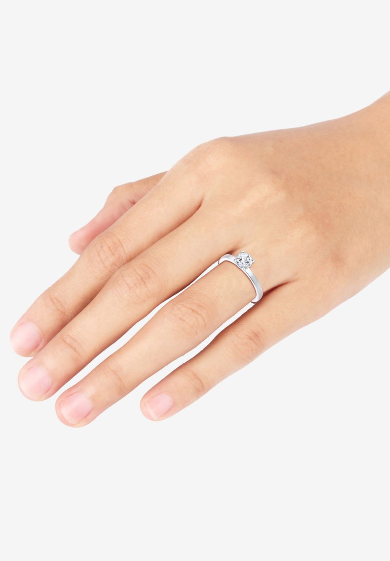 Ehering aus Sterlingsilber mit einem klaren runden Edelstein, der ein minimalistisches Banddesign aufweist. Glatte Textur, subtile Eleganz.