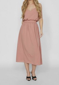 Vestido sin mangas en rosa empolvado con escote en V, cintura fruncida y falda midi fluida, combinado con sandalias de tacón negro de punta abierta.
