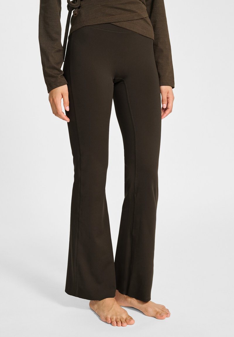 Brązowe spodnie o szerokich nogawkach, wykonane z elastycznego materiału. Gładka tekstura, dopasowany pas, szwy biegnące wzdłuż nóg oraz długość do kostek.