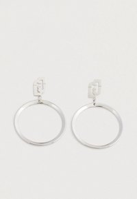 Orecchini a cerchio in metallo argentato con perni rettangolari che presentano un design astratto intagliato, presentati su uno sfondo bianco.