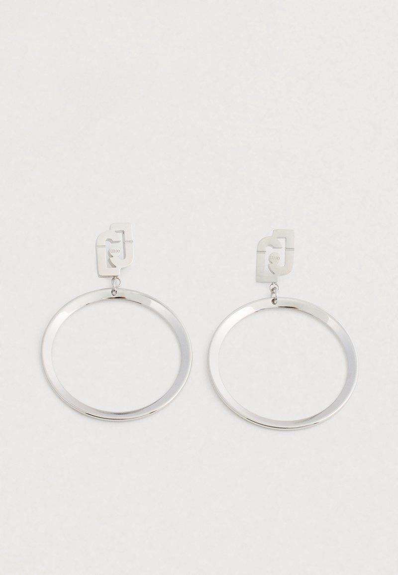 Orecchini a cerchio in metallo argentato con perni rettangolari che presentano un design astratto intagliato, presentati su uno sfondo bianco.