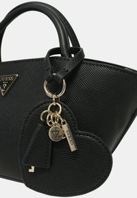 Borsa nera con texture, logo triangolare Guess, accessori in oro e portachiavi a forma di cuore con più ciondoli. Dettagli in finitura lucida.