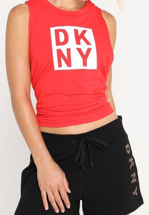 Czerwony krótki top bez rękawów z białym logo DKNY, połączony z czarnymi szortami z troczkiem i napisem DKNY po boku.