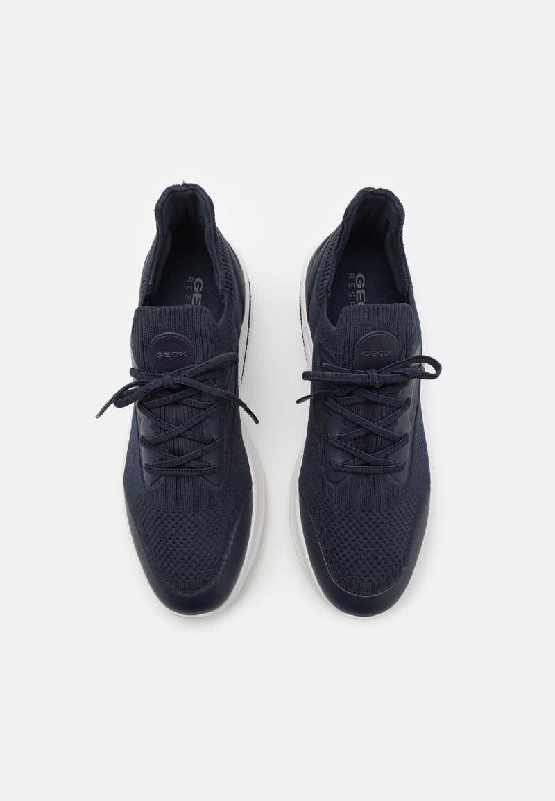 Sneakers blu navy realizzati in rete traspirante con una superficie testurizzata, dotati di punta arrotondata, chiusura con lacci e dettagli sulla suola in bianco.