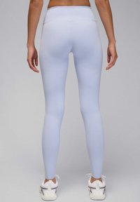 Leggings de talle alto en azul claro hechos de tela elástica, diseño ajustado, textura suave y sin patrones ni logotipos visibles.