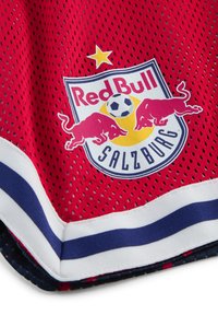 Maillot de sport en tissu en maille rouge et bleu marine, avec un logo circulaire du Red Bull Salzburg comportant deux taureaux rouges et une étoile blanche.