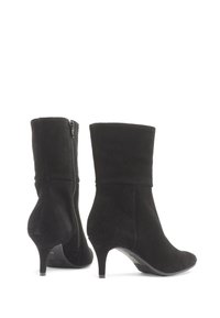 Par svart mocka midjekorta stövlar med spetsiga tår, sidodragkedjor och smala kittenklackar mot en vit bakgrund.