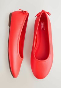 Rote Ballerinas mit einer glatten, glänzenden Oberfläche, abgerundetem Zehenbereich und einer kleinen Schleife an der Ferse. Braune Sohle.