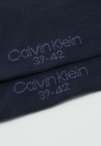 Jūriniai kojinės, pagamintos iš minkštos medžiagos, turinčios raukšlėtą tekstūrą. Išsiuvinėtas "Calvin Klein 39-42" šviesiai mėlyna spalva. Lygus paviršius.