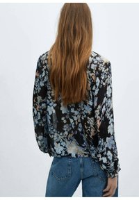 Floral blouse in lightweight, sheer black fabric with blue and peach flower patterns, featuring long sleeves and a relaxed fit.