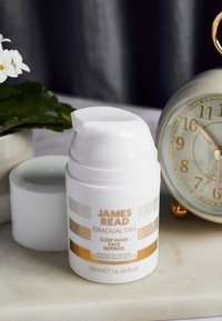 Flacone pompa bianco con accenti dorati, etichettato "James Read Gradual Tan Sleep Mask Face Retinol", 50ml, posizionato su una superficie in marmo.